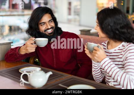 Cute affectionate indian couple sitting at table in city cafe Stock Photo