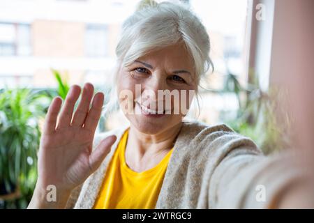 Portrait of smiling senior woman taking selfie at home Stock Photo