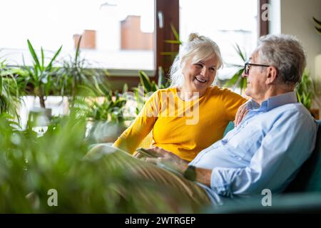Portrait of a happy senior couple sitting on sofa at home Stock Photo