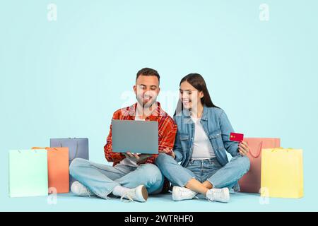 couple shops online with laptop paying via credit card, studio Stock Photo