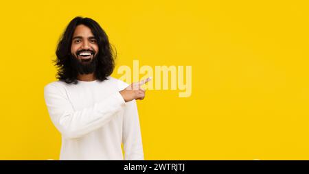Cheerful young indian man pointing at copy space Stock Photo