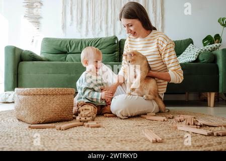 Mother holding cat and playing with son in the living room Stock Photo