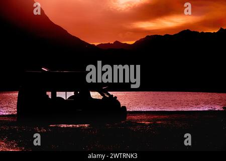A campervan is silhouetted against Lake Hawea at sunset in the Otago region of southern New Zealand. Stock Photo