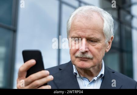 Senior Business man in a suit looking concentrated at his mobile phone Stock Photo