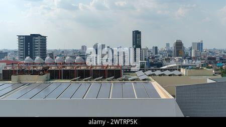 Solar panels on the roof, Solar energy panels installed in straight long rows with skyscrapers at the background Stock Photo