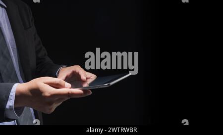 Businessman hand touching tablet screen on black background with blank for copy space Stock Photo