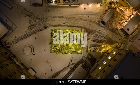 Drone photography of decorated christmas trees in a city between buildings during winter cloudy night Stock Photo