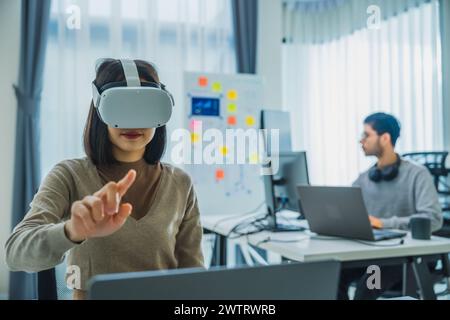 Asian and Indian developer program coding sent to virtual reality headset to implement ai project at office Stock Photo