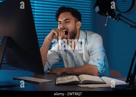 Tired young man working late in office Stock Photo