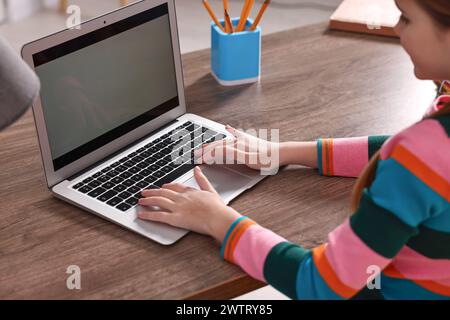 E-learning. Girl using laptop during online lesson at table indoors, closeup Stock Photo