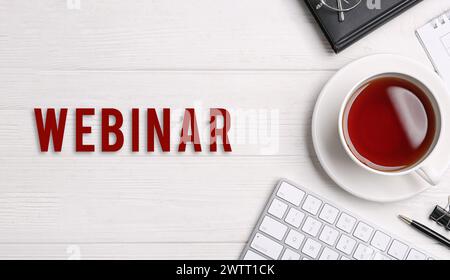 Webinar. Computer keyboard, tea and stationery on white wooden table, flat lay. Banner design Stock Photo