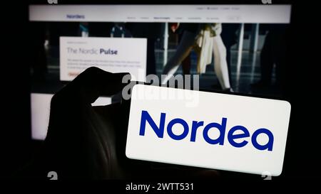 Person holding smartphone with logo of Finnish financial services company Nordea Bank Abp in front of website. Focus on phone display. Stock Photo