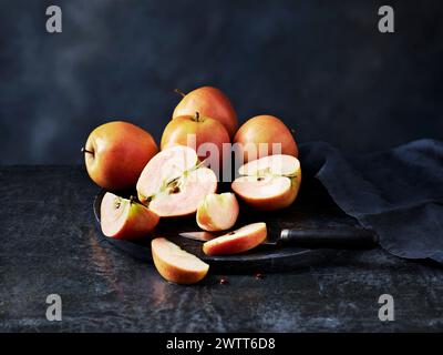 Sliced apples and an old knife on a dark, textured background Stock Photo