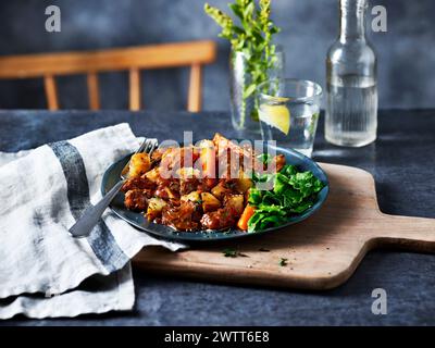 A delicious plate of roasted vegetables served on a rustic wooden board Stock Photo