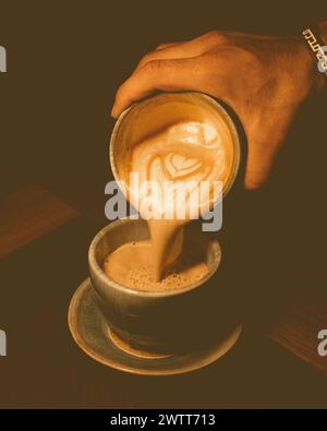 Pouring  espresso coffee from hand into cup Stock Photo