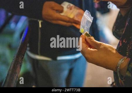 Hands exchanging cash for a small bag at night Stock Photo