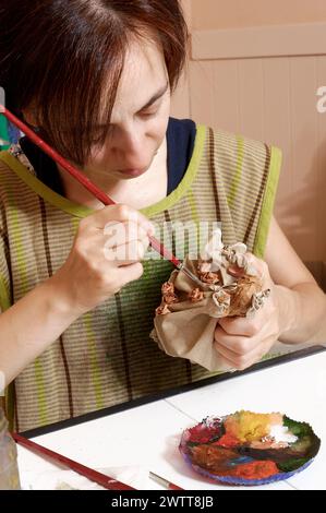 Artist concentrating on painting a small sculpture. Stock Photo