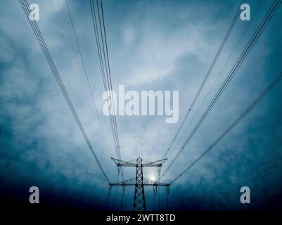 Electricity pylons reaching into a moody sky Stock Photo