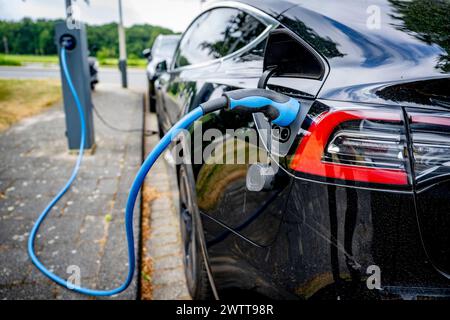 Electric car plugged in at a charging station. Stock Photo