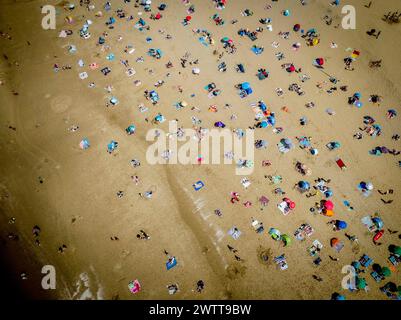 A bustling beach scene from above, with people enjoying the sand and sea. Stock Photo