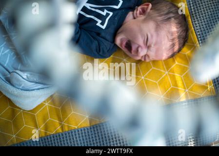 Newborn baby crying on a yellow blanket Stock Photo