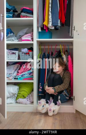 Little girl hiding in a colorful wardrobe Stock Photo