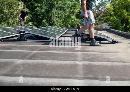 Workers installing solar panels on a roof on a sunny day Stock Photo