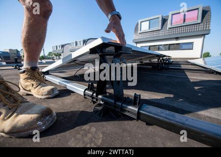 Worker installing a solar panel system on a rooftop on a sunny day Stock Photo