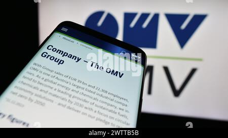 Mobile phone with website of Austrian oil and gas company OMV Aktiengesellschaft in front of business logo. Focus on top-left of phone display. Stock Photo