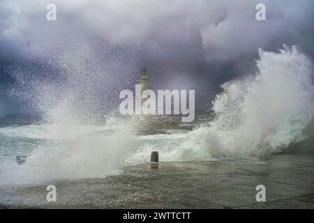 Majestic waves crash against a lighthouse during a storm Stock Photo
