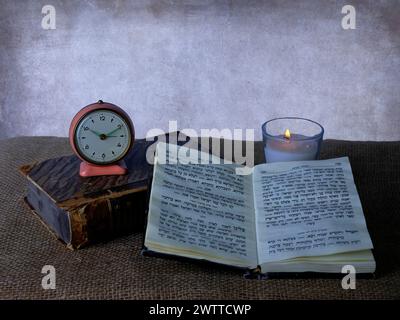 Timeless serenity with a vintage clock, flickering candle, and an open book Stock Photo