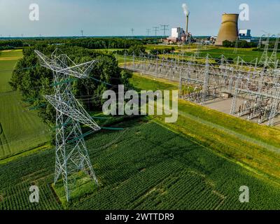 Aerial view of power lines leading to an industrial plant amidst green fields Stock Photo