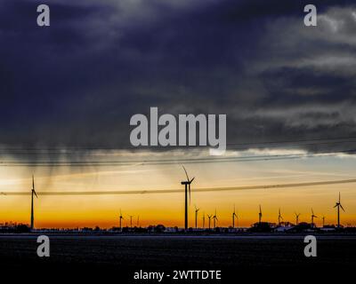 Dramatic sunset behind a silhouette of wind turbines Stock Photo