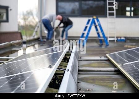Workers installing solar panels on a rooftop Stock Photo