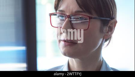 Female programmer designing code on a computer screen in the office. Stock Photo