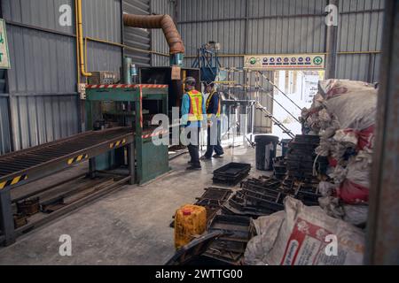Workers monitoring machinery in a plastic recycling factory, Thailand Stock Photo