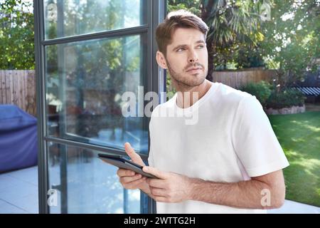 Man holding a tablet looking thoughtfully outside Stock Photo