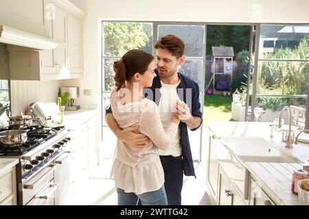 Couple embracing lovingly in a sunny kitchen. Stock Photo