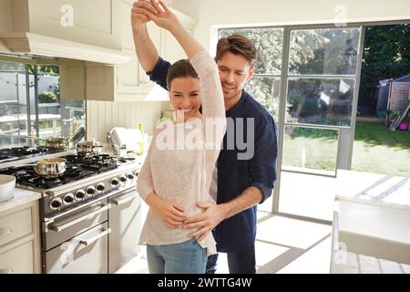 Couple dancing in a sunlit kitchen Stock Photo