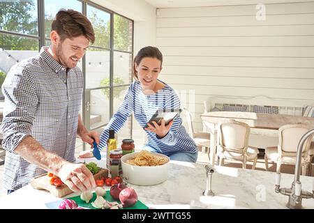 Couple cooking together in a bright kitchen Stock Photo
