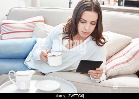 Woman relaxing with coffee and tablet on a sofa Stock Photo