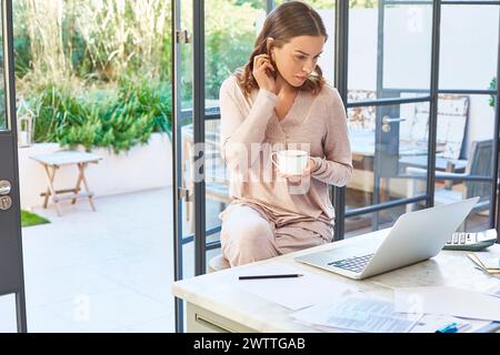 Woman using a laptop at home with a coffee cup Stock Photo