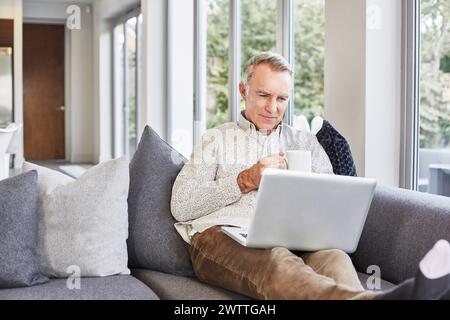 Man working on laptop while sitting on a couch Stock Photo