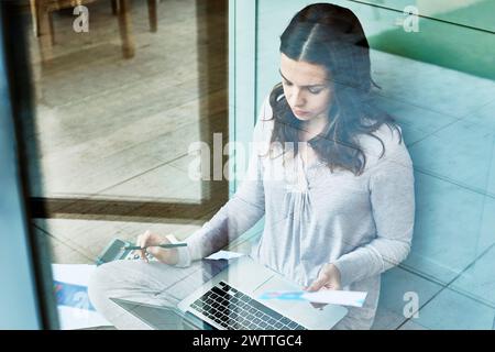 Woman working on laptop behind glass Stock Photo