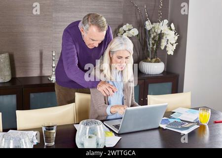 Senior couple using a laptop at a dining table Stock Photo