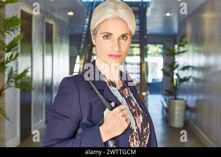 Professional woman standing in a modern office hallway Stock Photo