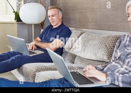 Two people using laptops on a sofa Stock Photo