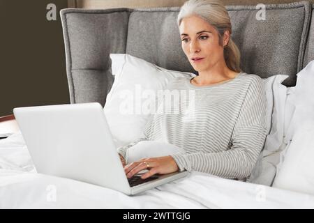 Woman working on laptop in bed Stock Photo