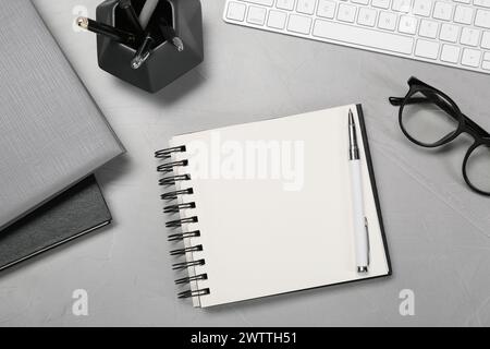 Flat lay composition with notebooks, keyboard and glasses on light grey table Stock Photo