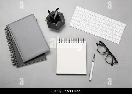 Flat lay composition with notebooks, keyboard and glasses on light grey table Stock Photo